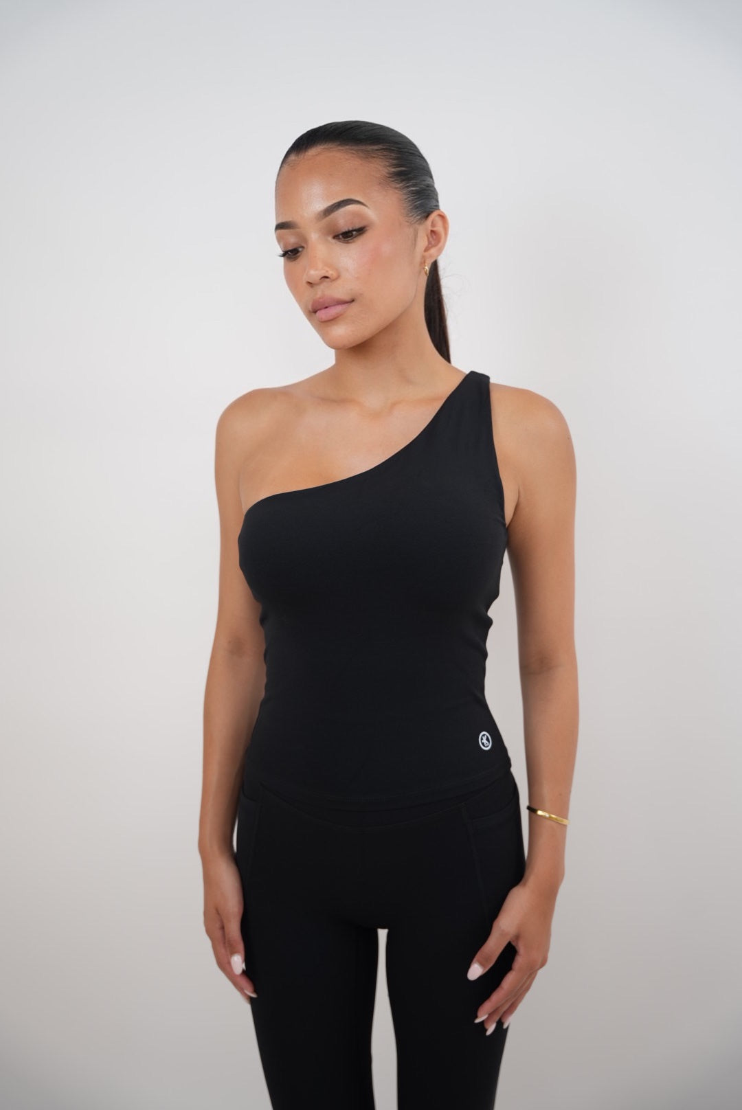 Woman wearing a black one-shoulder jumpsuit on a white background