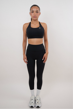 Person wearing a black sports bra and leggings set on a white background