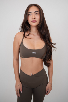 Woman wearing a green sports bra and leggings with a plain background