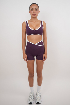 Person wearing a purple sports bra and shorts set on a plain background
