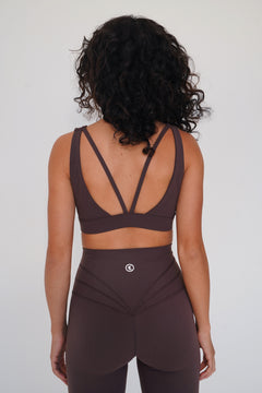 Person wearing a brown sports bra and leggings set on a plain background