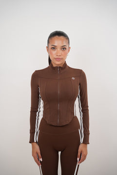 Person wearing a brown athletic outfit with white stripes on a plain background