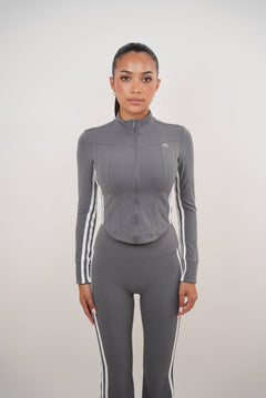 Woman wearing a gray athletic outfit with white stripes on a light gray background